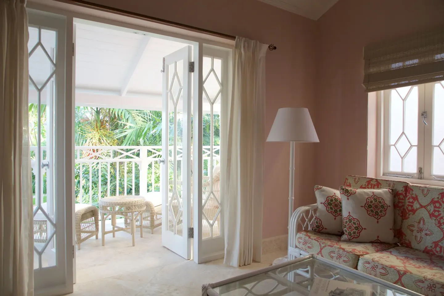 Guest room sitting area opening to a leafy balcony at Cobblers Cove.
