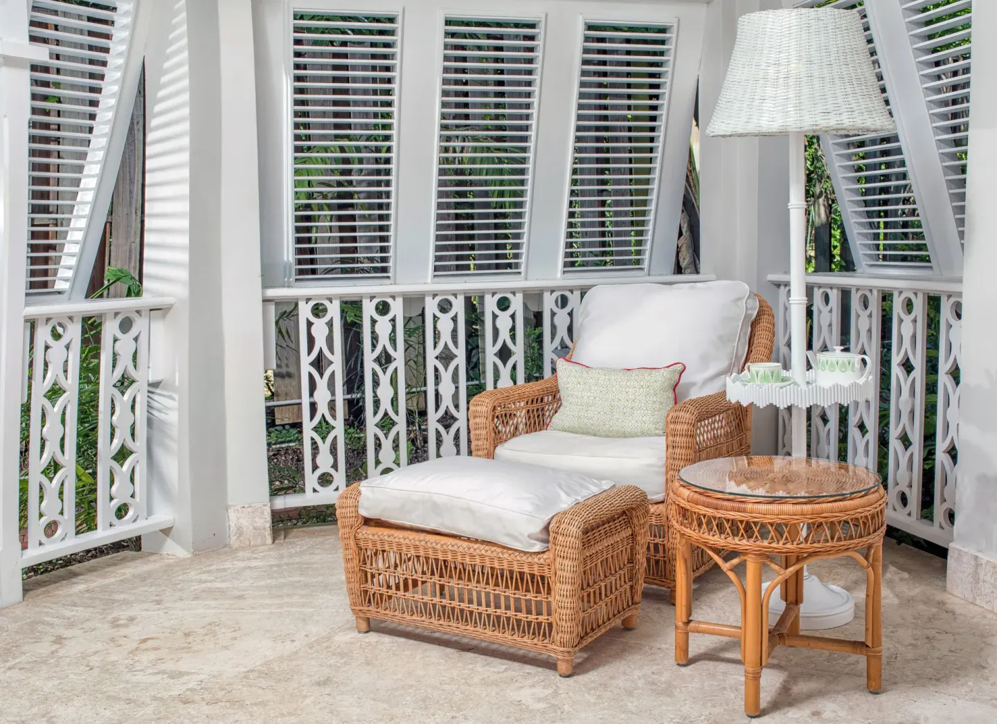 Wicker lounge chair and side table on a shuttered balcony at Cobblers Cove.