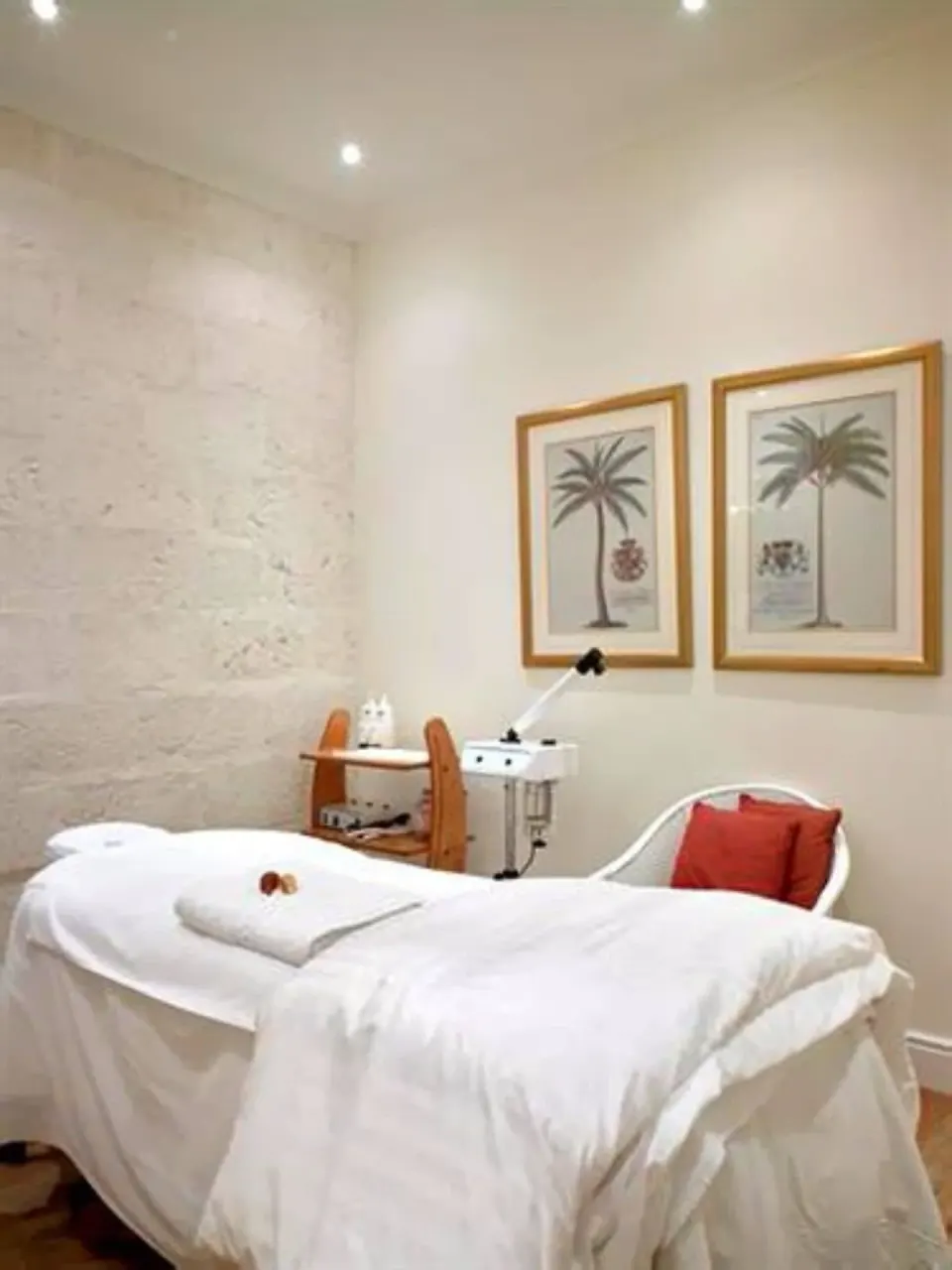Spa treatment room with a draped treatment bed and palm artwork at Cobblers Cove.