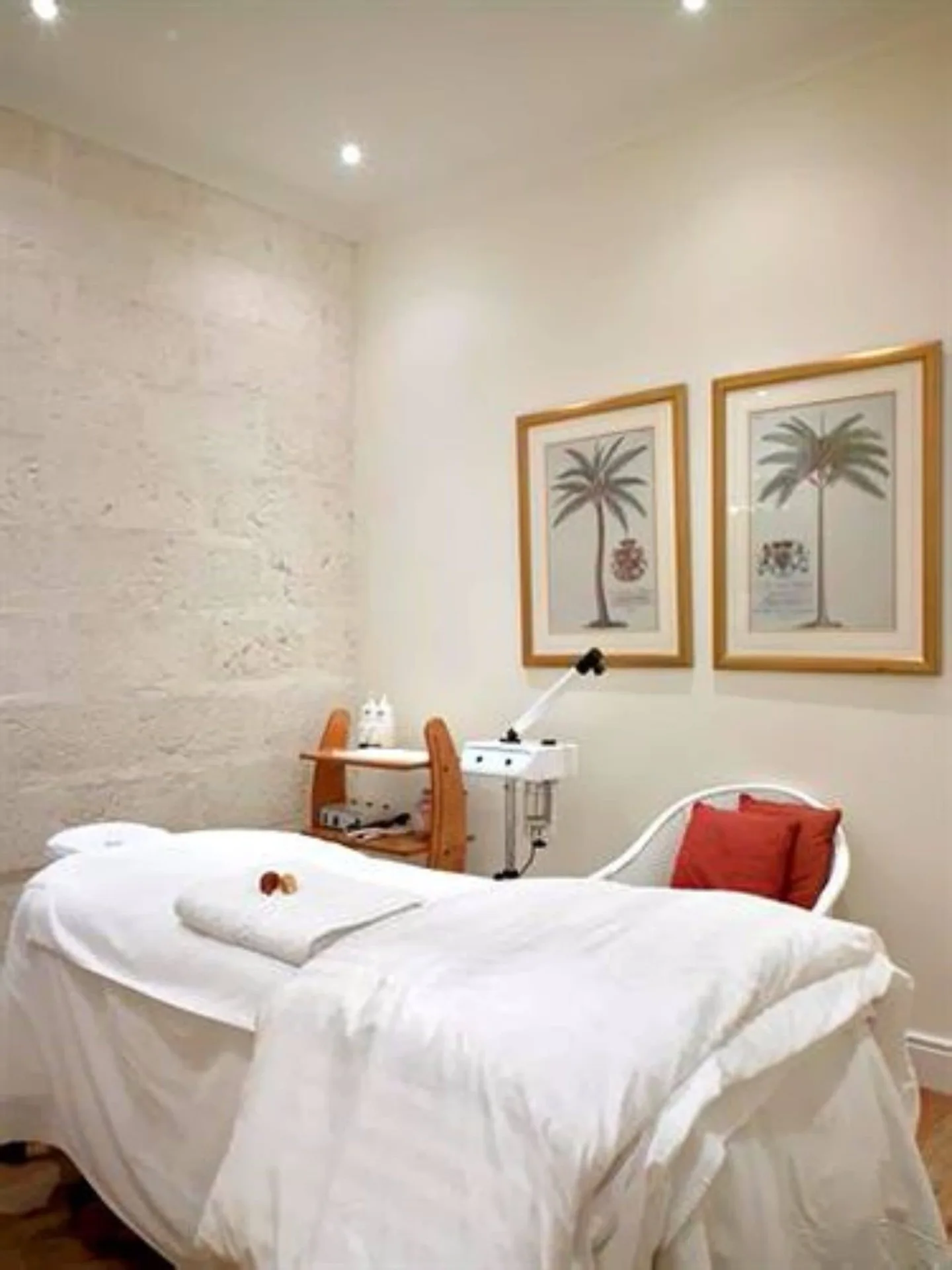 Spa treatment room with a draped treatment bed and palm artwork at Cobblers Cove.