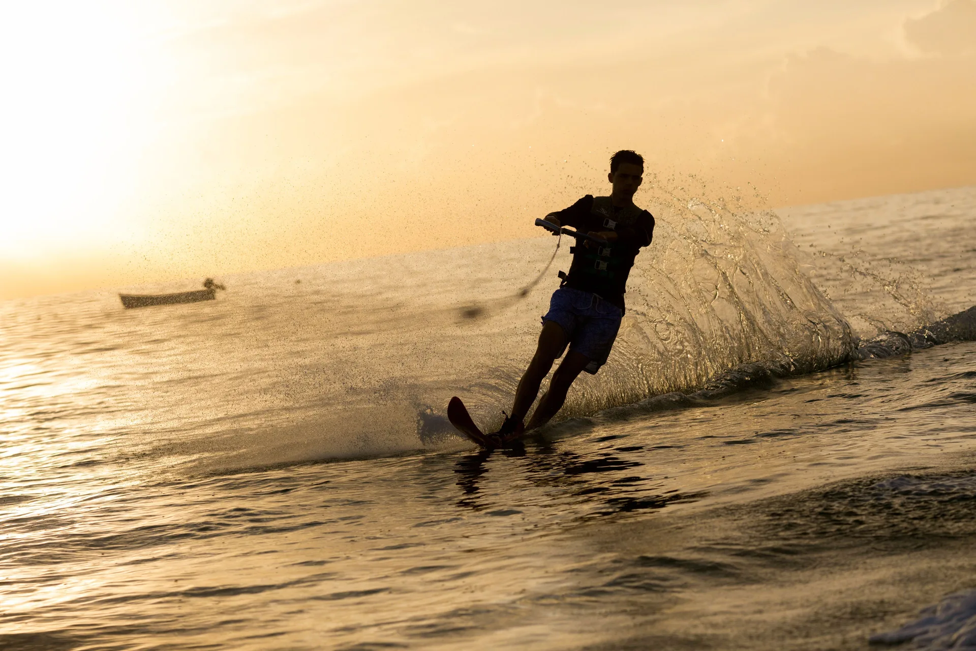 A water skier cuts across the sea at sunset near Cobblers Cove.