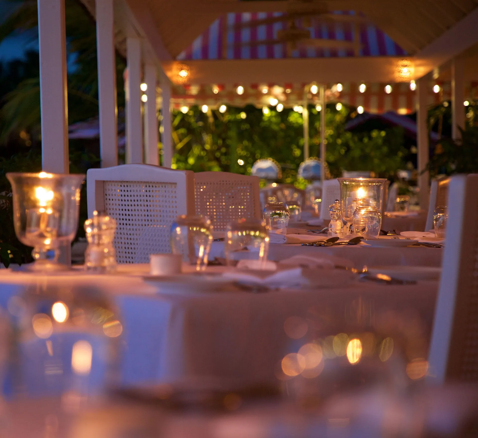 Candlelit dining tables on a covered terrace at Cobblers Cove.
