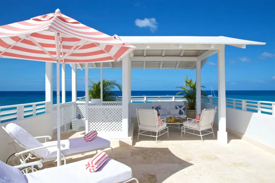 Private oceanfront terrace for Camelot at the Great House at Cobblers Cove with loungers and seating.