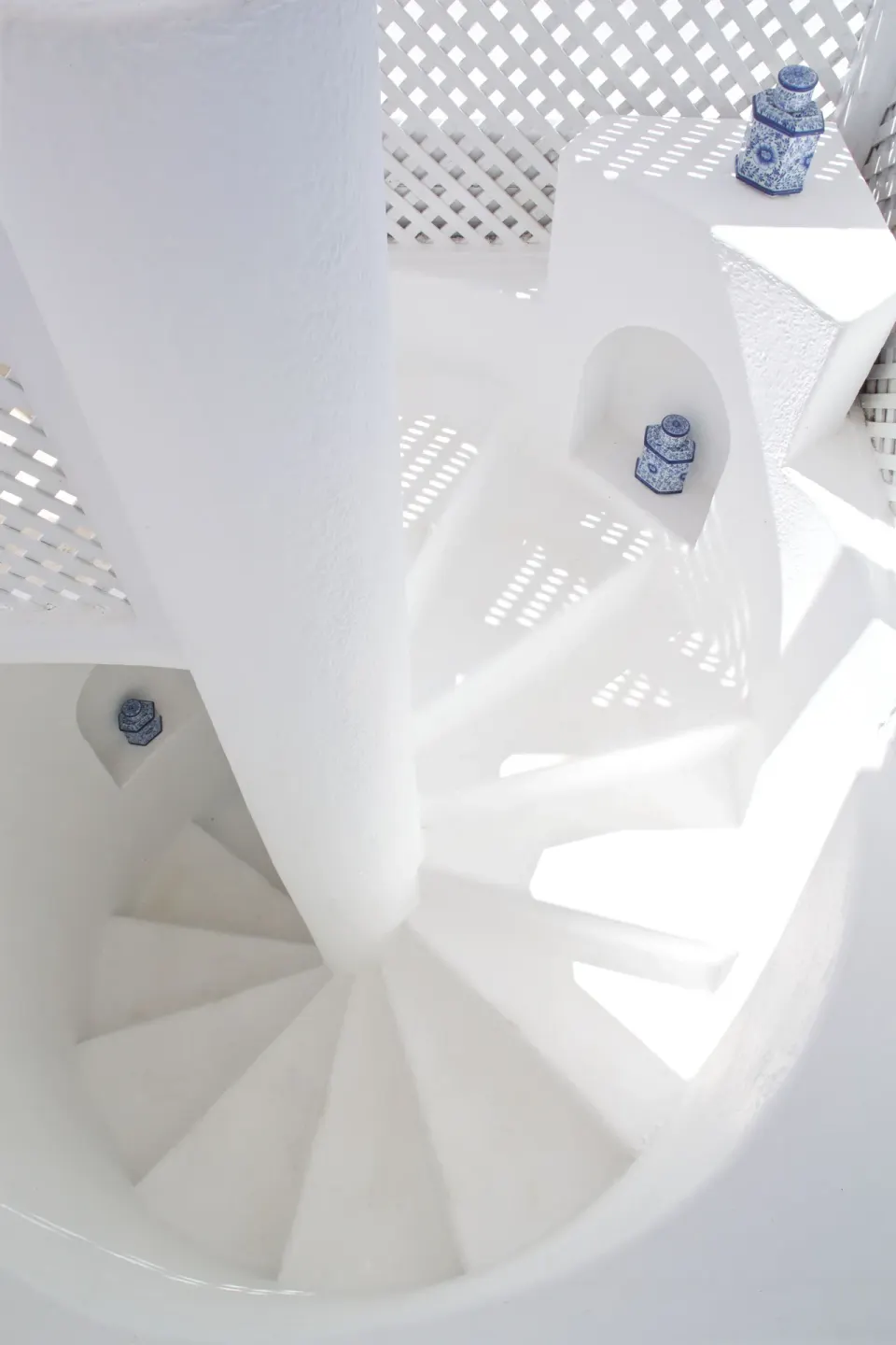 White spiral staircase in Camelot at the Great House at Cobblers Cove with blue ceramic jars.