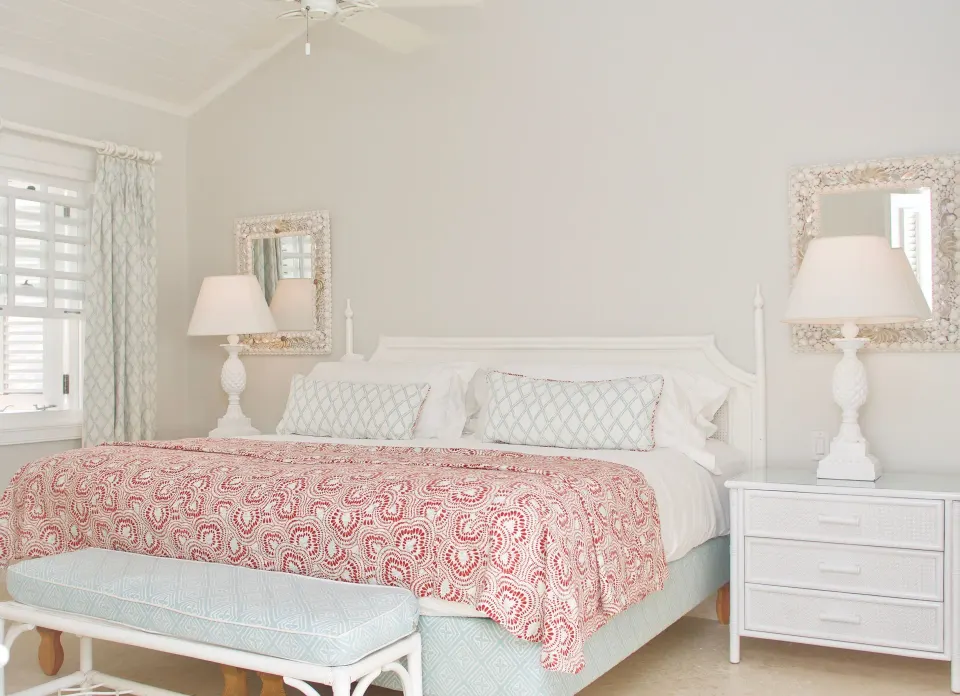 Ocean Front Suite bedroom with king bed and red patterned coverlet at Cobblers Cove.
