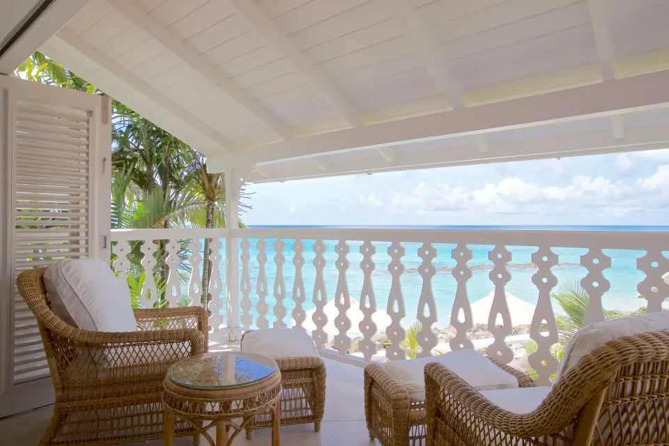Ocean Front Suite balcony with wicker chairs and turquoise sea view at Cobblers Cove.