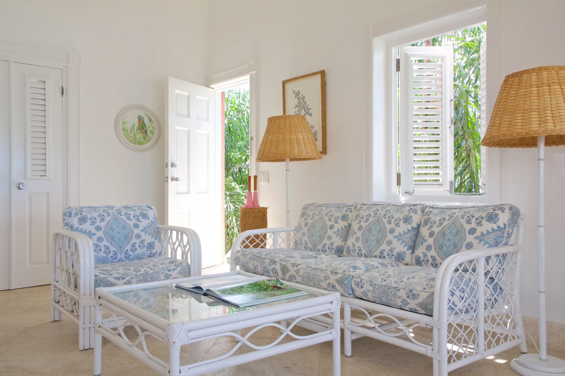 Ocean Front Suite sitting room with wicker sofa, armchair and open garden door at Cobblers Cove.