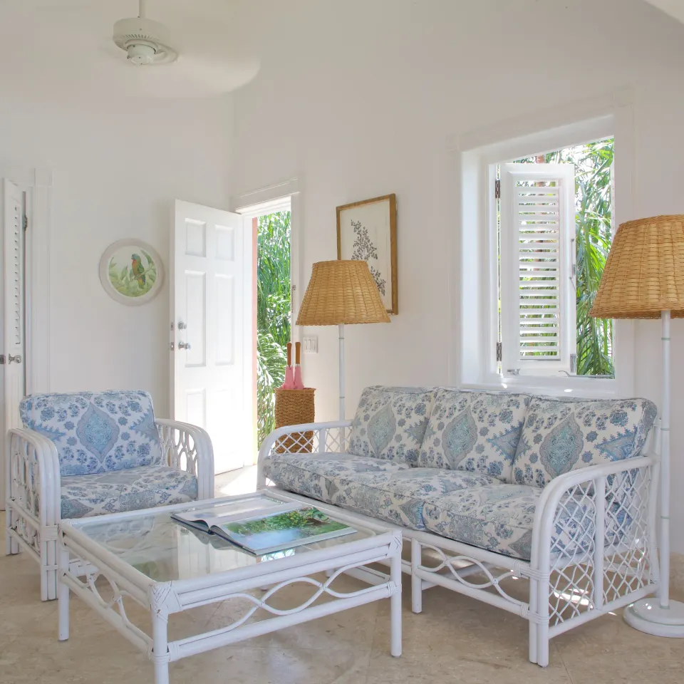 Royal Circle Suite sitting room with wicker seating and open garden door at Cobblers Cove.