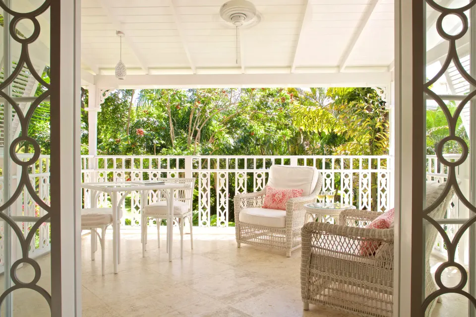 Royal Circle Suite terrace with wicker chairs and garden view at Cobblers Cove.