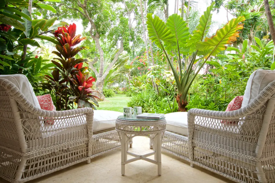 Upper Circle Suite terrace with wicker chairs and tropical garden at Cobblers Cove.