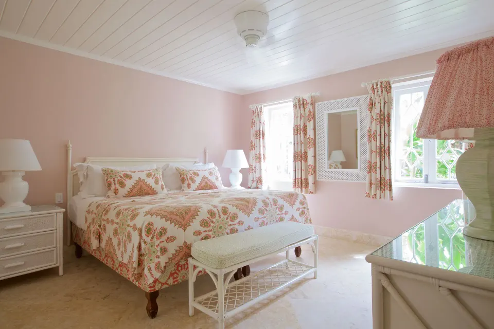 Upper Circle Suite king bedroom with pink walls and patterned linens at Cobblers Cove.