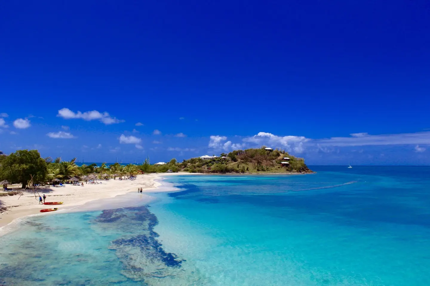 Aerial view of a sandy bay with clear blue water at Cocobay Resort.