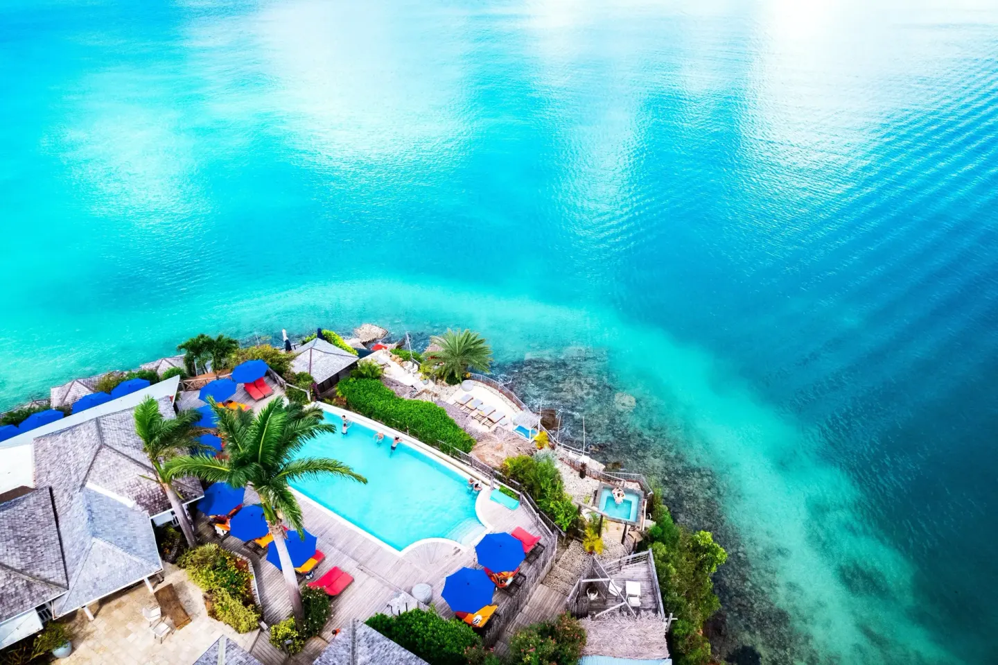 Aerial view of the clifftop pool and turquoise coastline at Cocobay Resort.