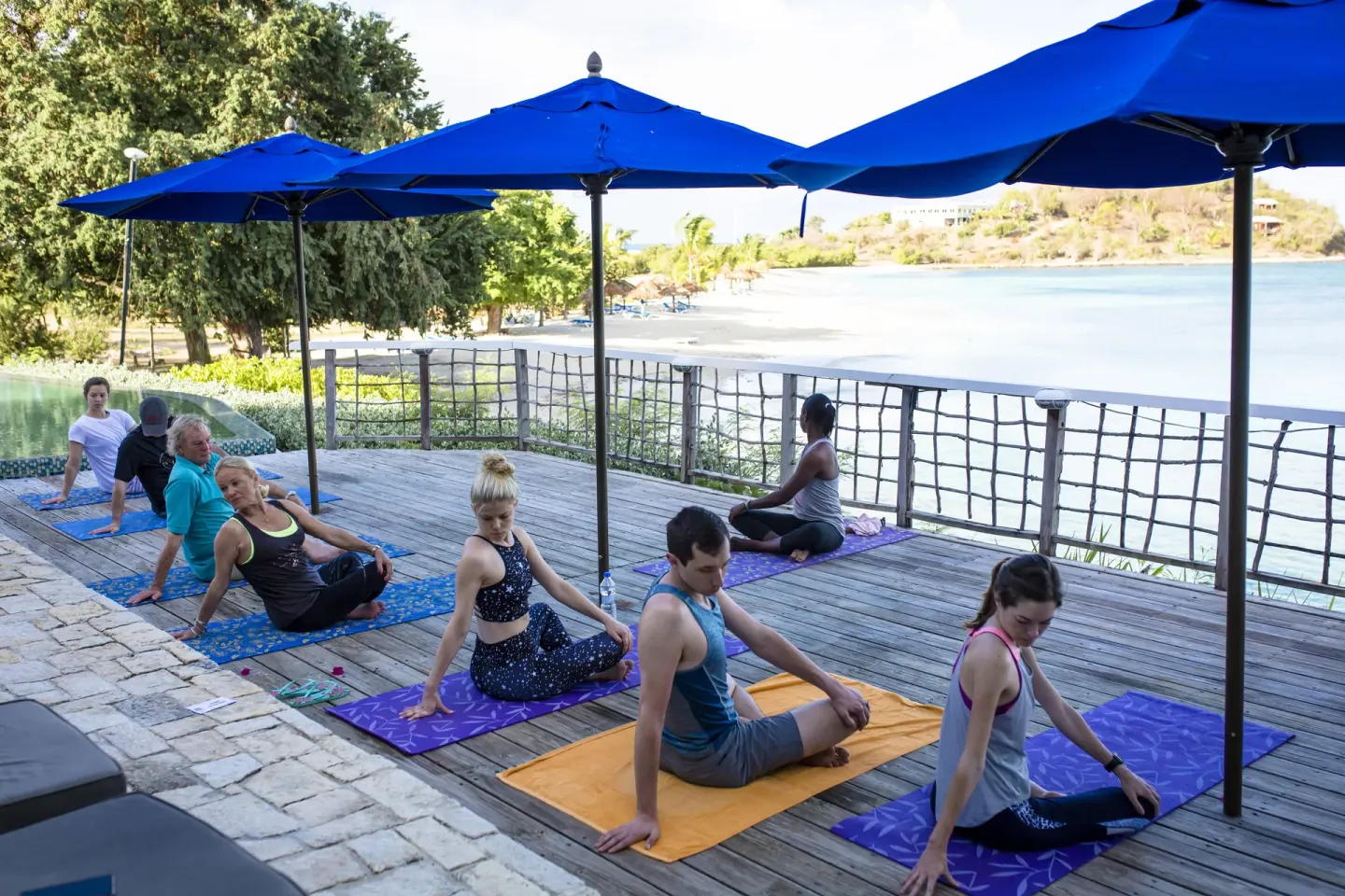 Group yoga class on a deck overlooking the beach at Cocobay Resort.
