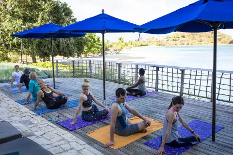 Group yoga class on a deck overlooking the beach at Cocobay Resort.