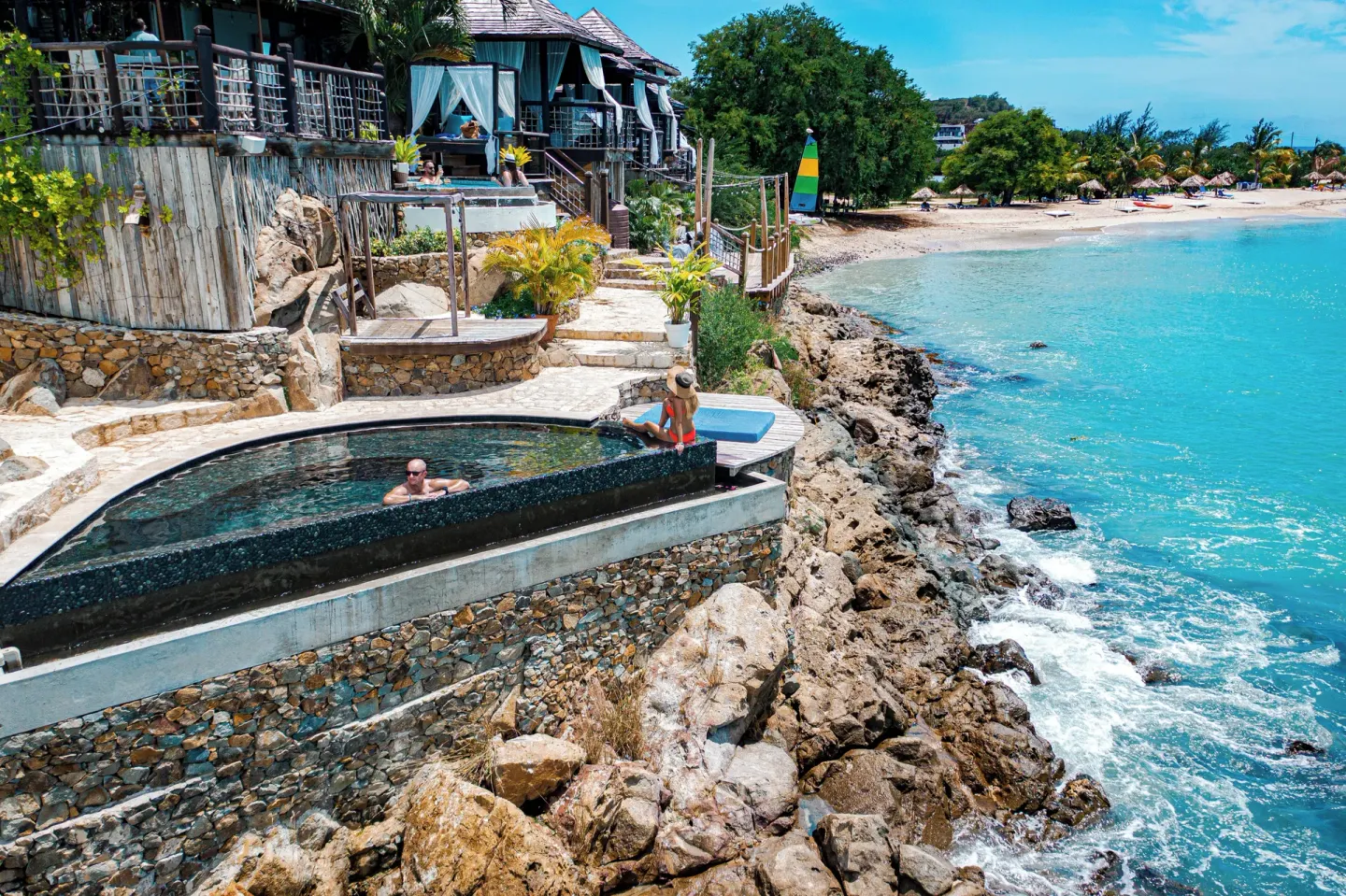 Cliffside plunge pool above rocks and turquoise water at Cocobay Resort.
