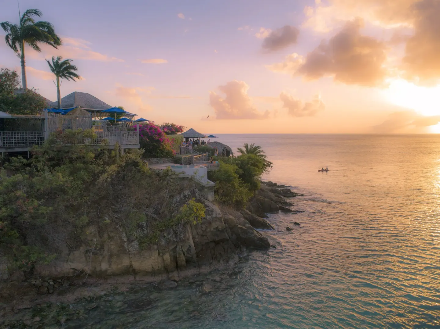 Cliffside sunset view over the sea and resort terraces at Cocobay Resort.