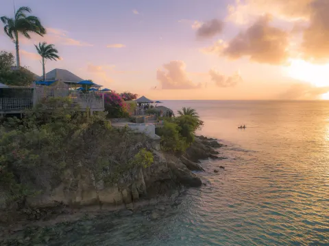 Cliffside sunset view over the sea and resort terraces at Cocobay Resort.