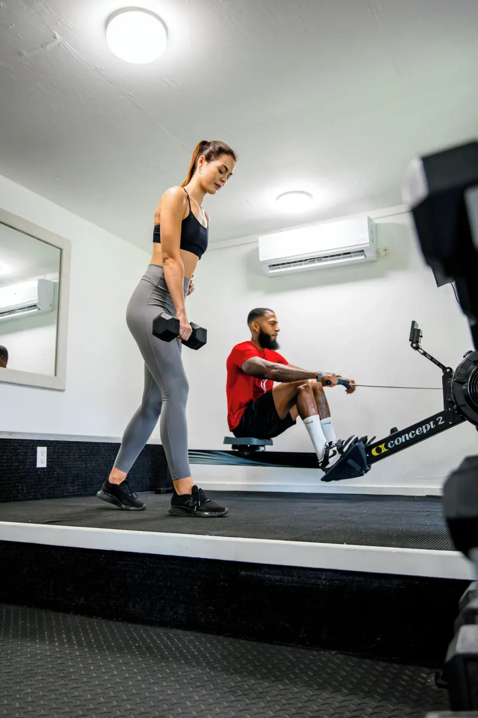 Two guests exercising with dumbbells and a rowing machine at Cocobay Resort.