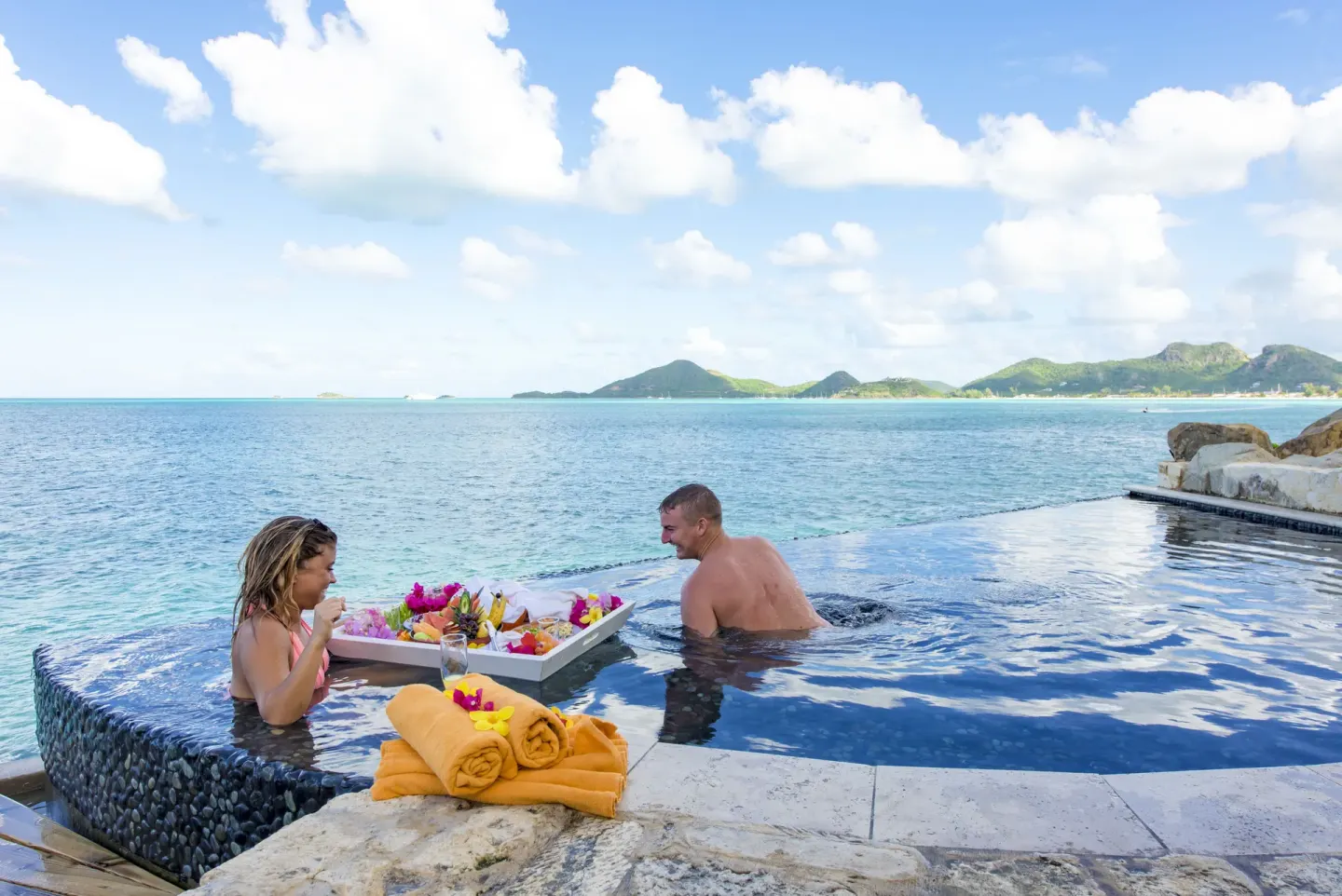 Guests enjoy a floating tray in an infinity pool at Cocobay Resort.