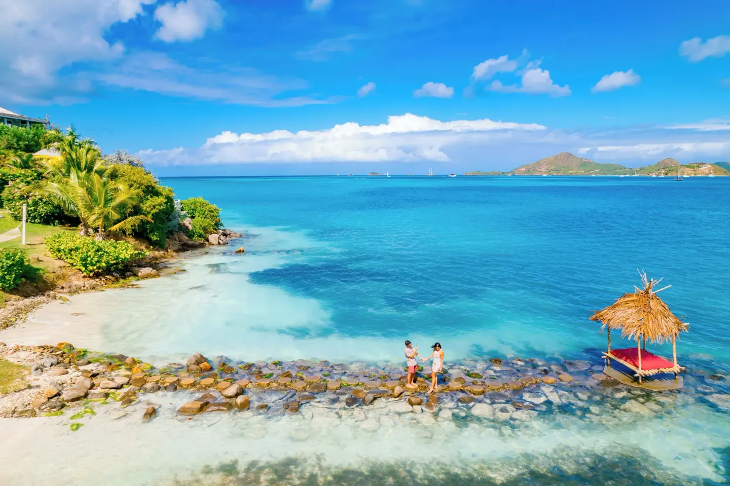 Aerial view of a rocky shoreline, thatched platform, and blue bay at Cocobay Resort.