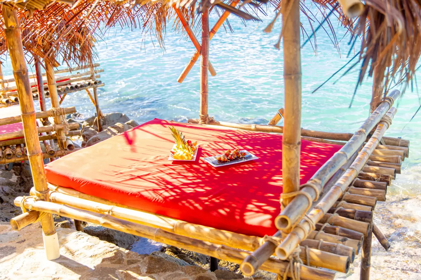 Bamboo daybed with fruit by the turquoise sea at Cocobay Resort.