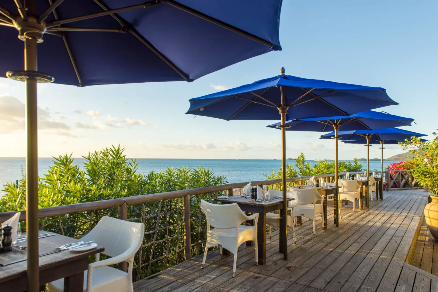 Oceanview terrace tables sit beneath blue umbrellas at Cocobay Resort.