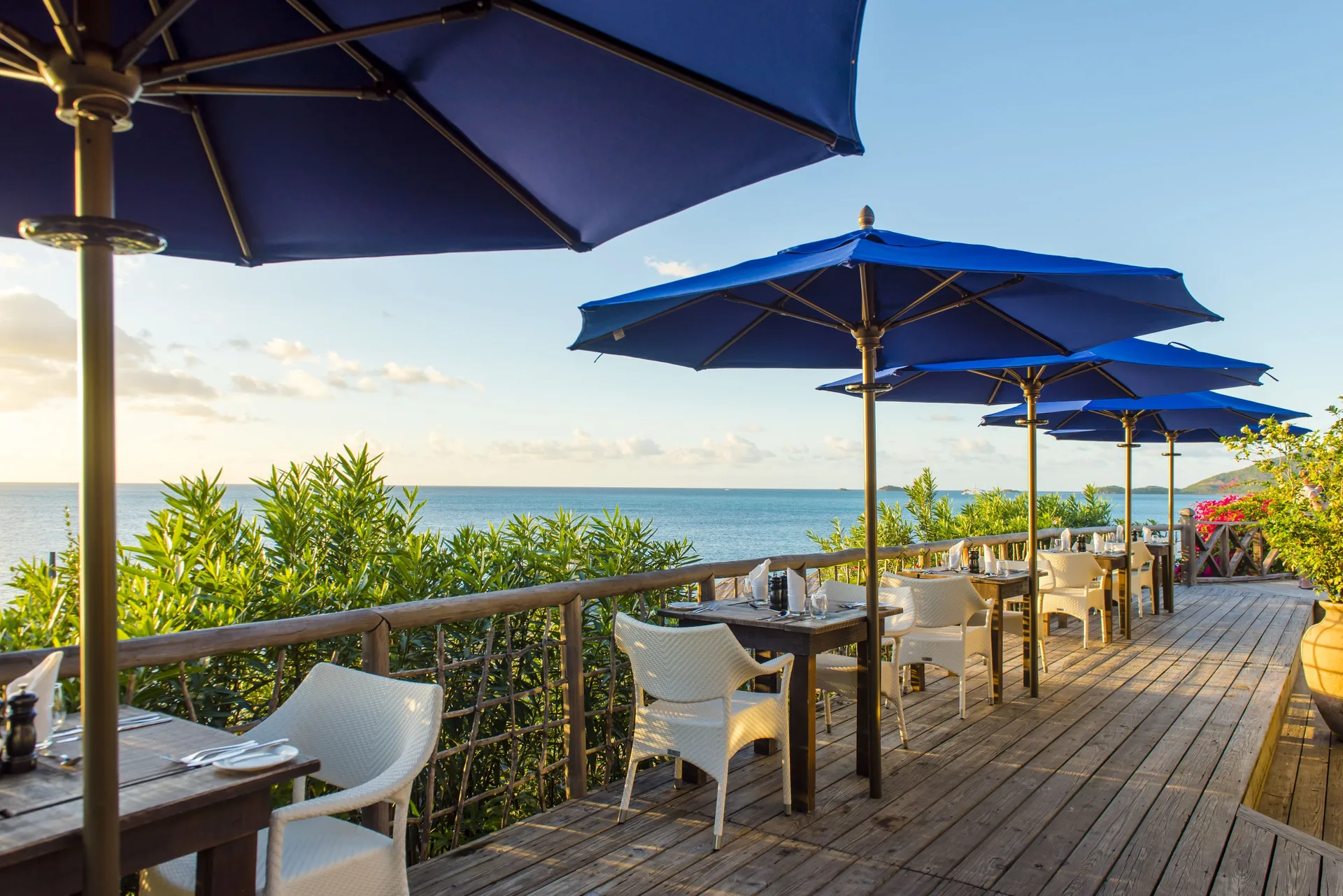 Oceanview terrace tables sit beneath blue umbrellas at Cocobay Resort.