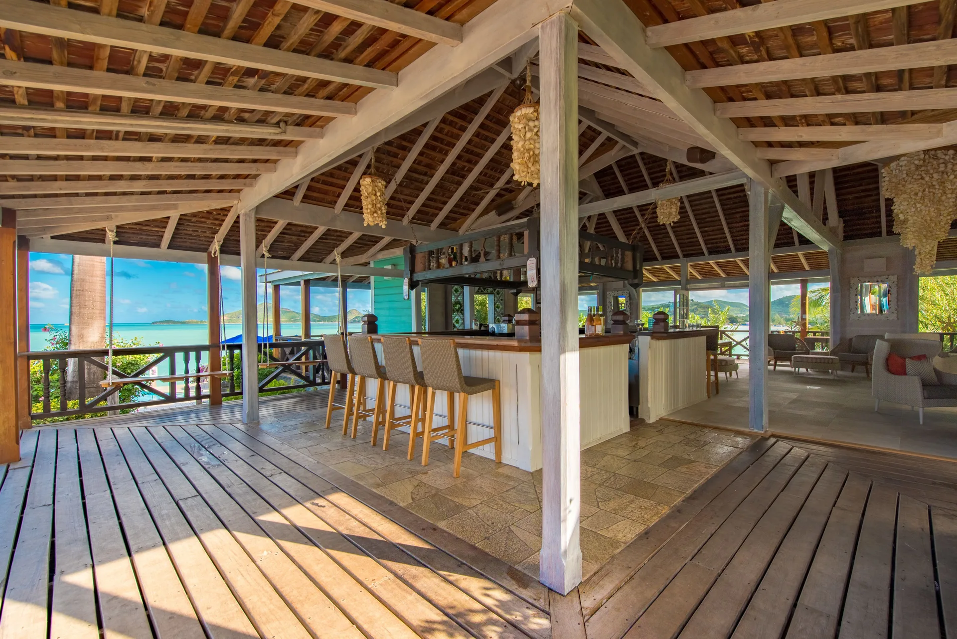 Open-air bar with stools and sea views at Cocobay Resort.