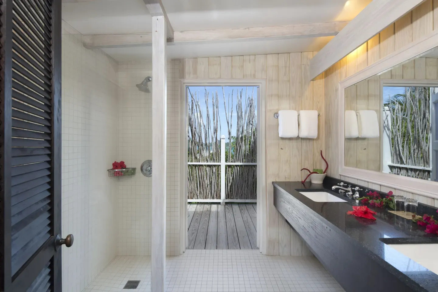 Deluxe Cottage bathroom at Cocobay Resort with open shower, vanity, and deck doorway.