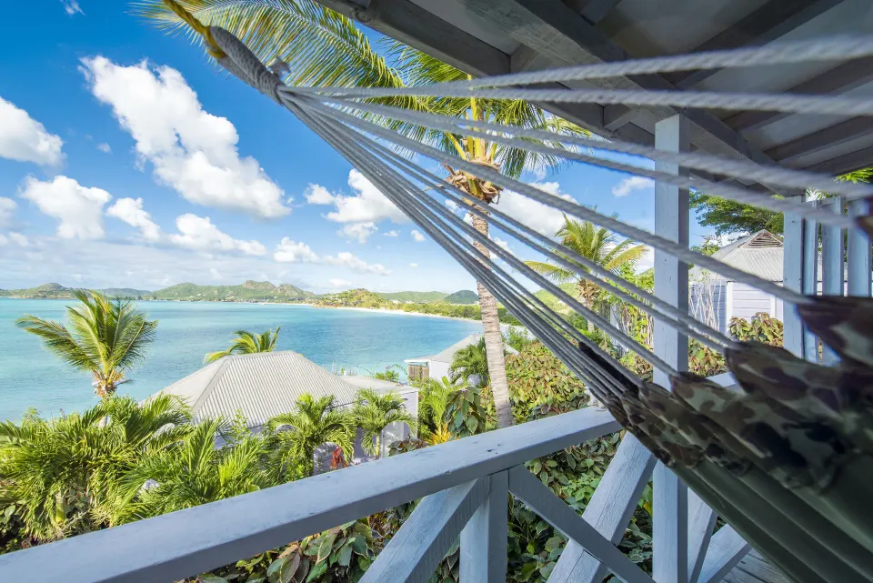 Deluxe Cottage hammock at Cocobay Resort overlooking palms, rooftops, and turquoise bay.