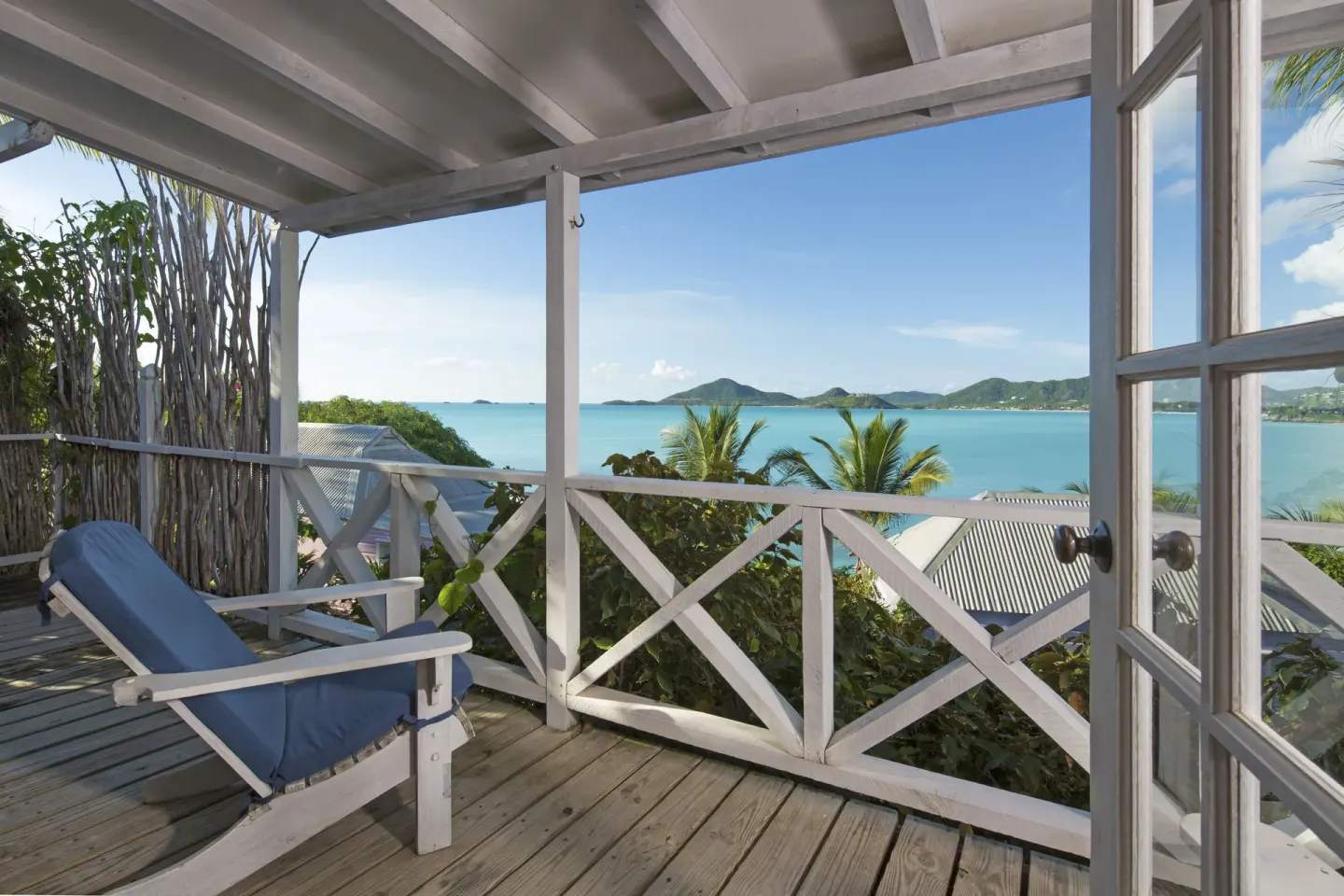 Deluxe Cottage veranda at Cocobay Resort with a blue cushioned chair and bay view.