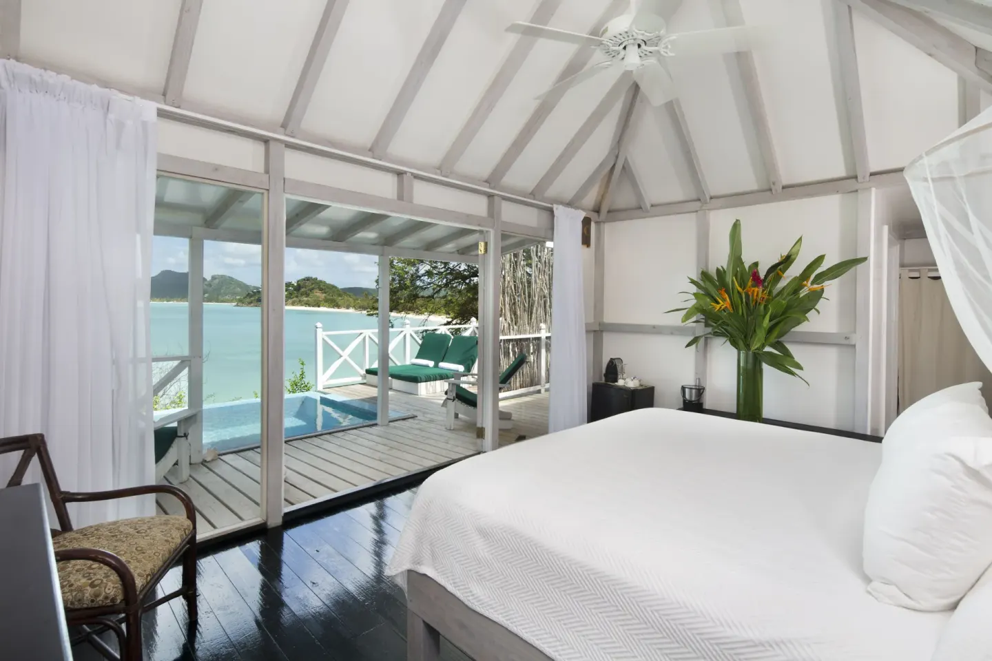 Premium Suite bedroom at Cocobay Resort with sea-facing deck and private pool beyond the glass doors.