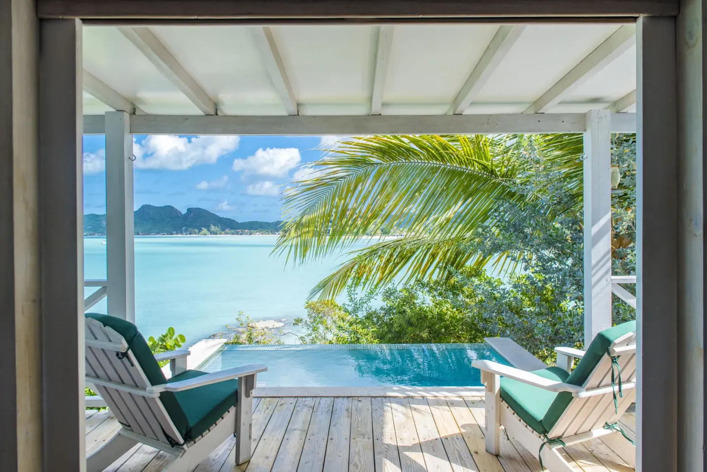 Private pool deck at Cocobay Resort with two cushioned chairs facing the sea.