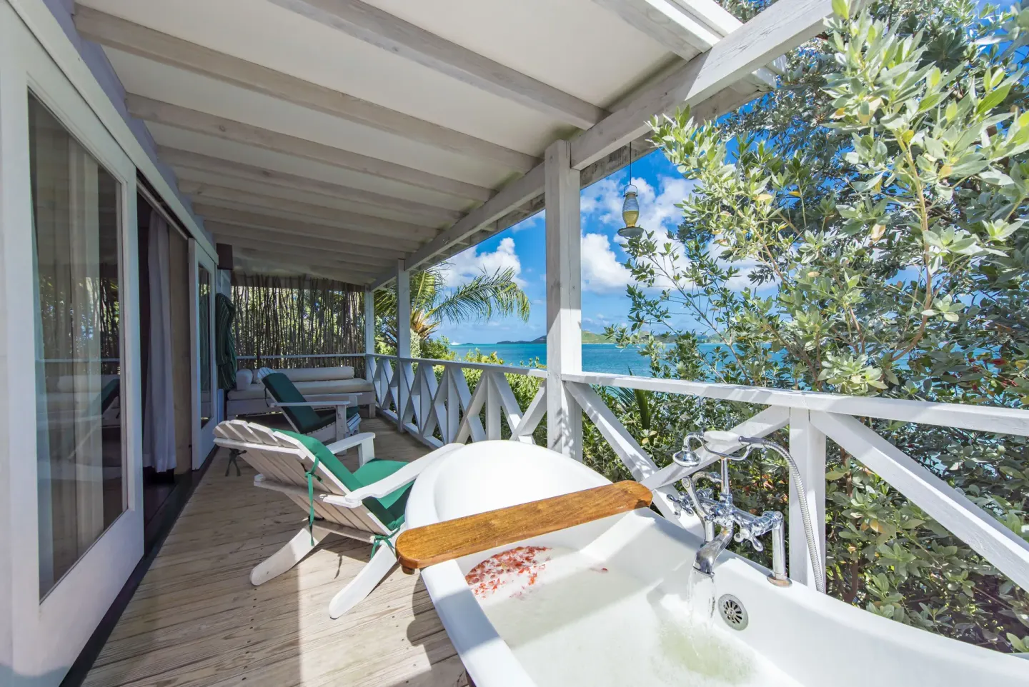 Sea-facing veranda at Cocobay Resort with an outdoor tub, loungers, and water views.