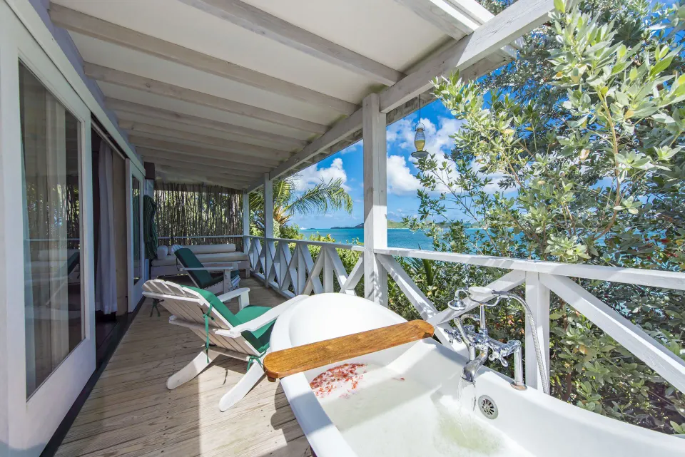 Sea-facing veranda at Cocobay Resort with an outdoor tub, loungers, and water views.