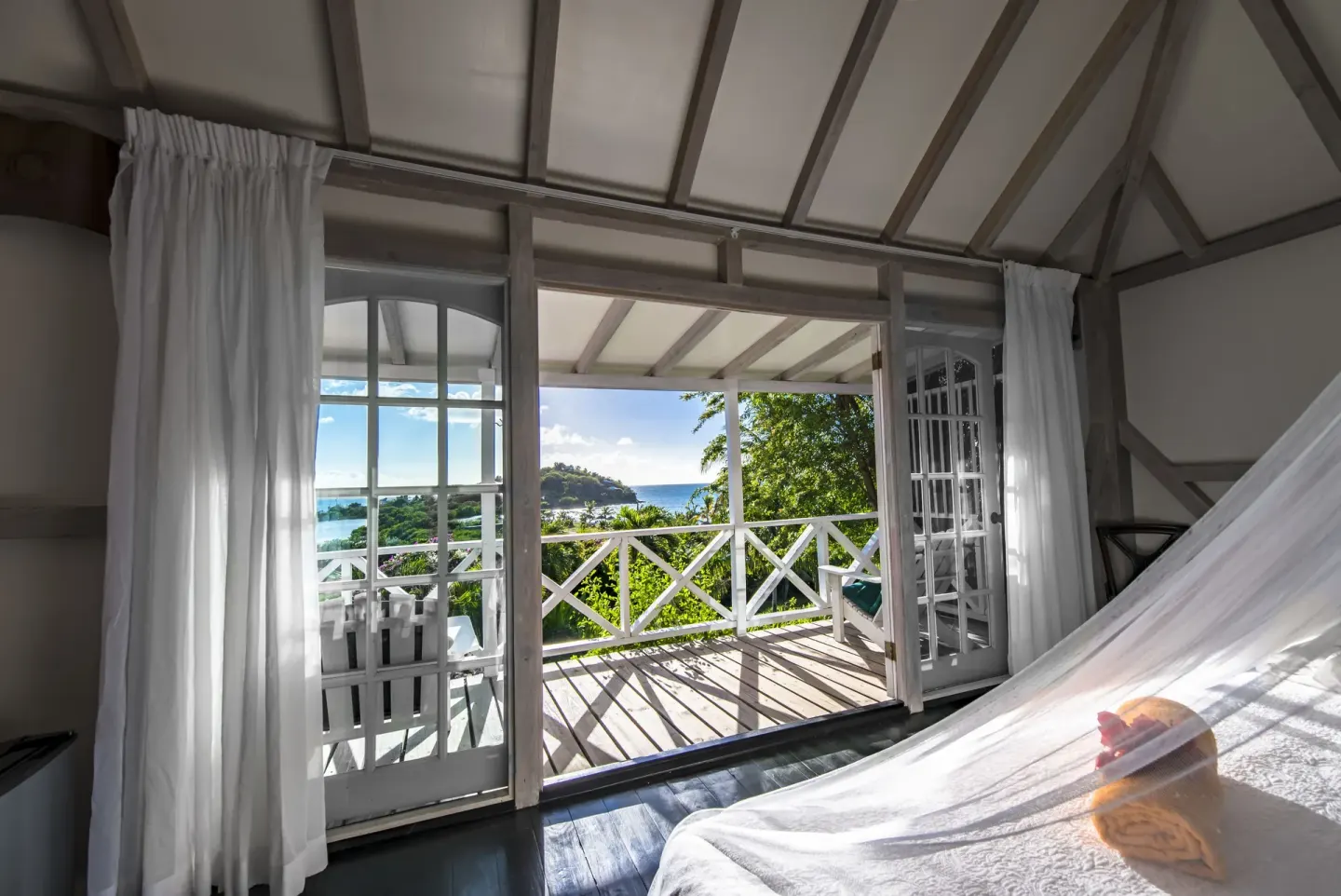 Standard Cottage Garden View bed beside open balcony doors at Cocobay Resort.