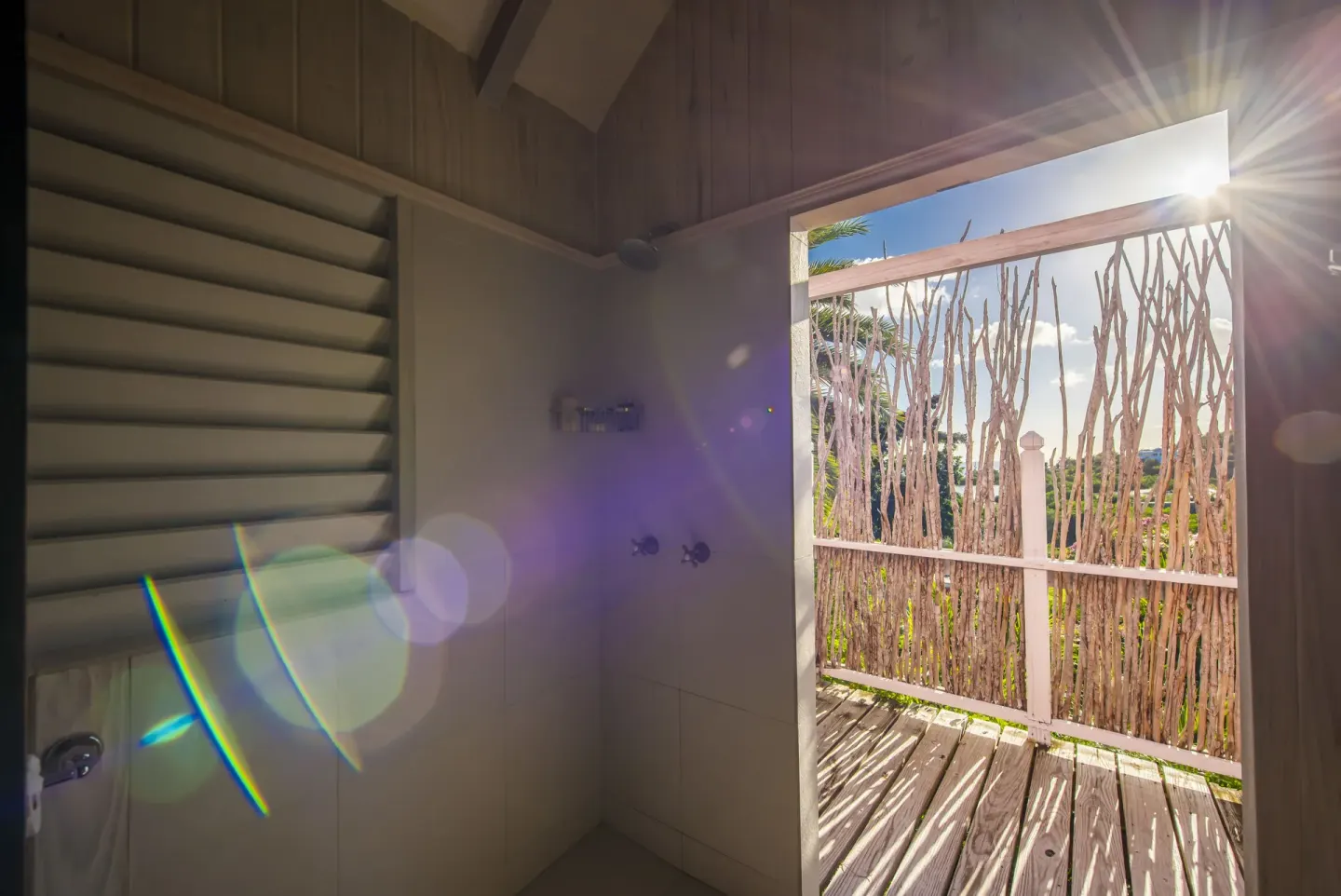 Standard Cottage Garden View shower opening to a sunlit deck at Cocobay Resort.