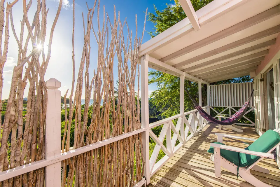 Standard Cottage Garden View veranda with hammock and lounge chair at Cocobay Resort.