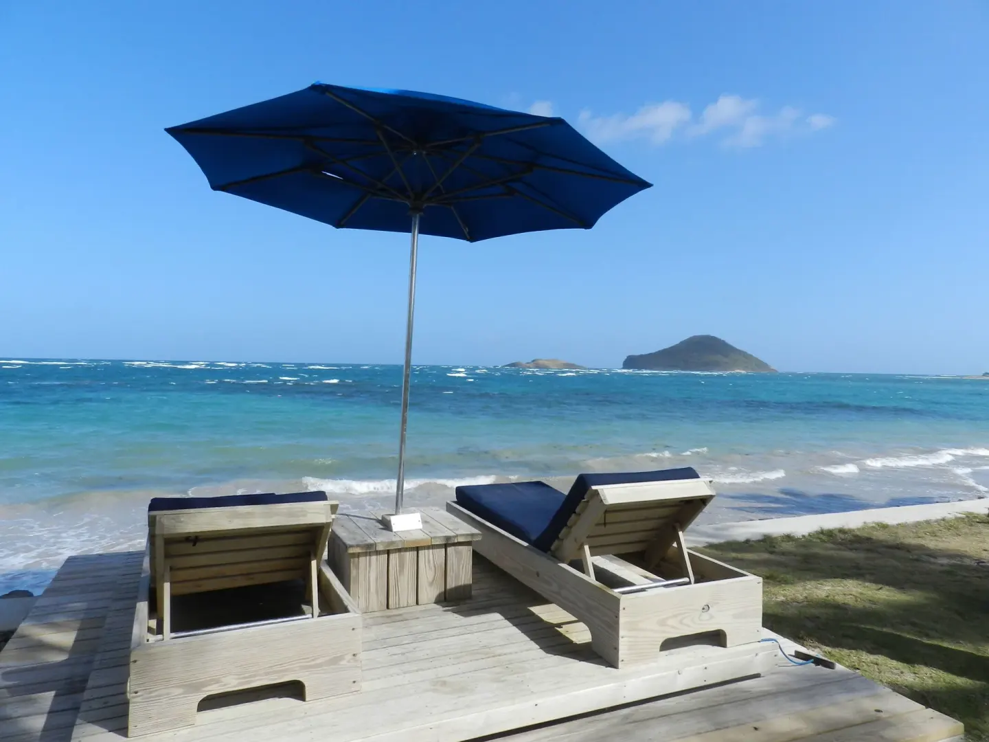 Two beach loungers under a blue umbrella at Coconut Bay Beach Resort & Spa.