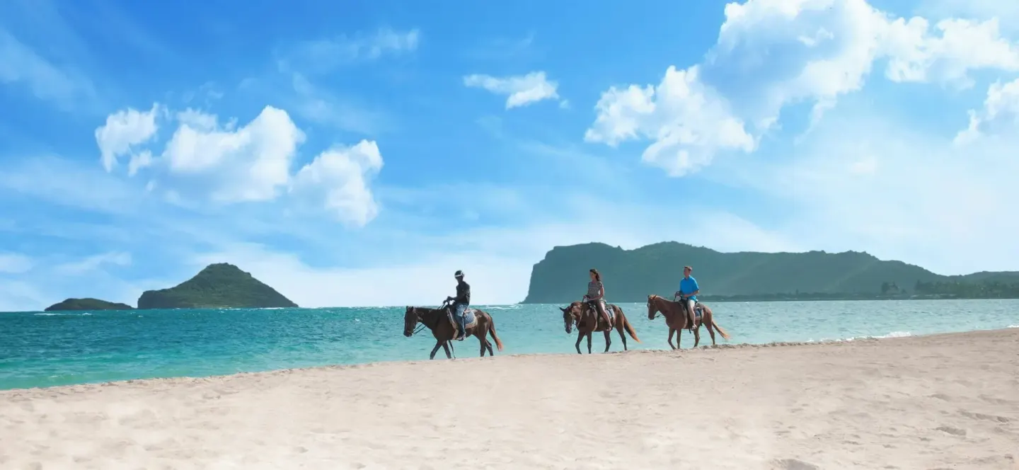 Guests ride horses along the beach near Coconut Bay Beach Resort & Spa.