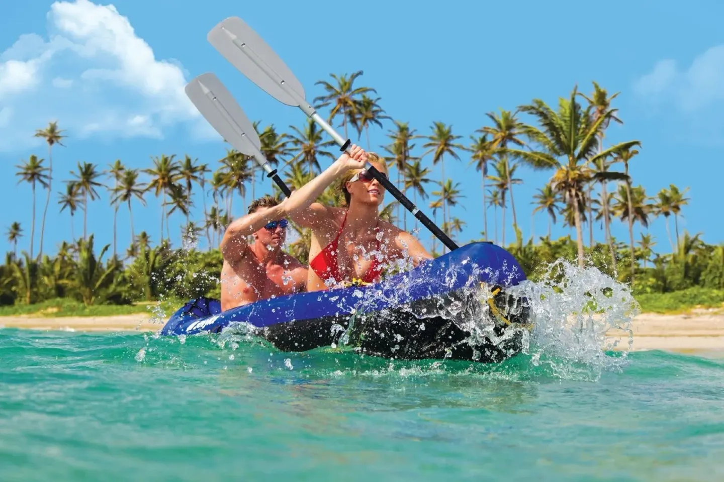 Two guests kayak in turquoise water by Coconut Bay Beach Resort & Spa.
