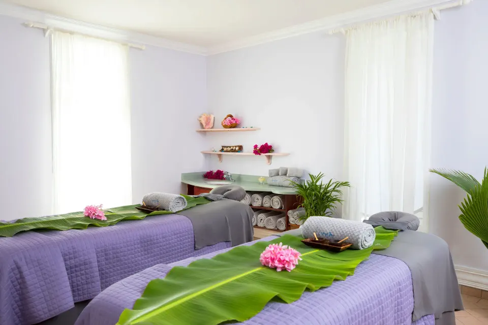 Spa treatment room with two tables and floral accents at Coconut Bay Beach Resort & Spa.
