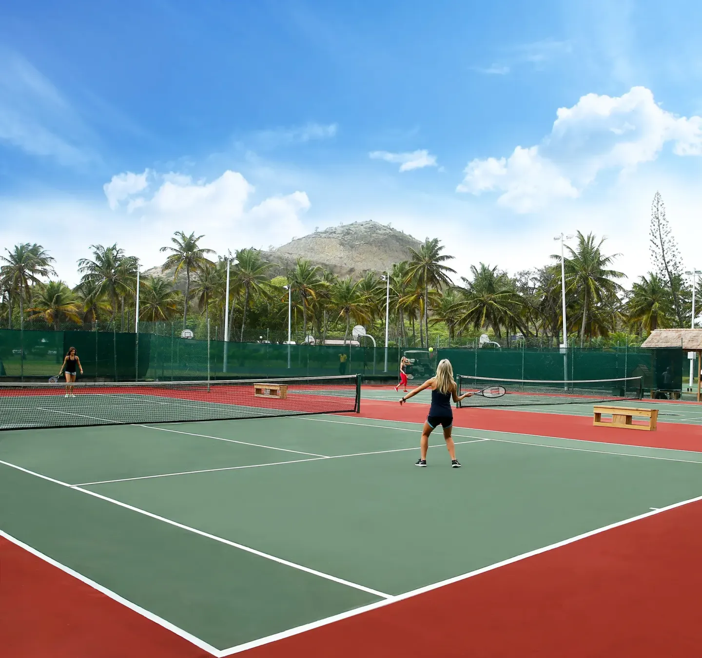 Guests play tennis on outdoor courts at Coconut Bay Beach Resort & Spa.