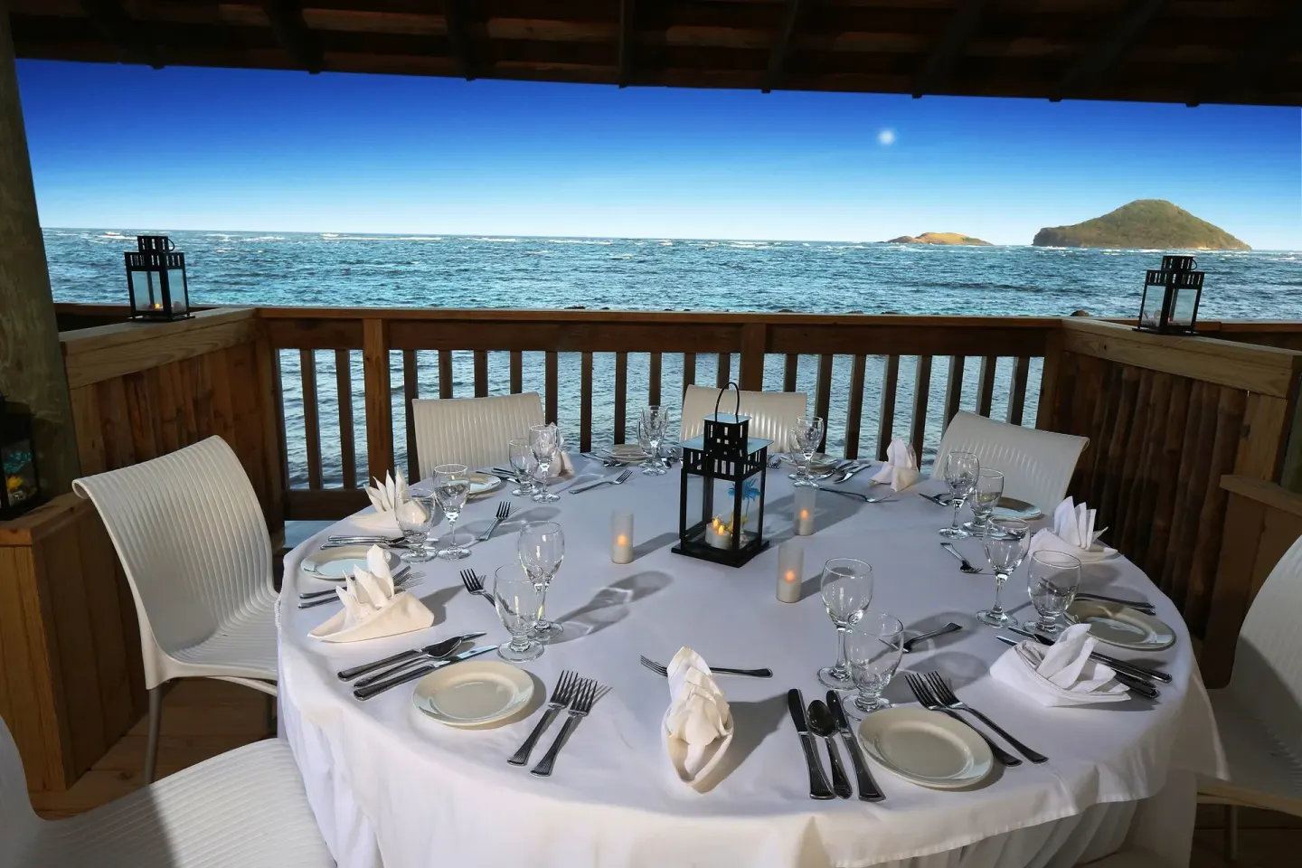 Oceanfront round dining table set for dinner at Coconut Bay Beach Resort & Spa.