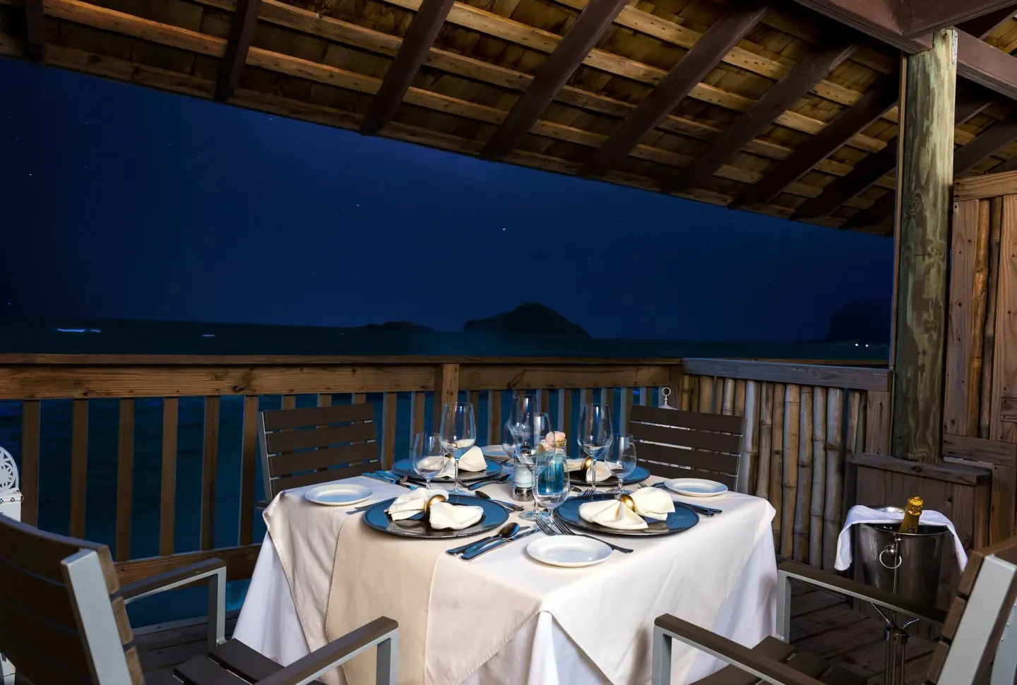 Candlelit oceanfront dining table at night at Coconut Bay Beach Resort & Spa.