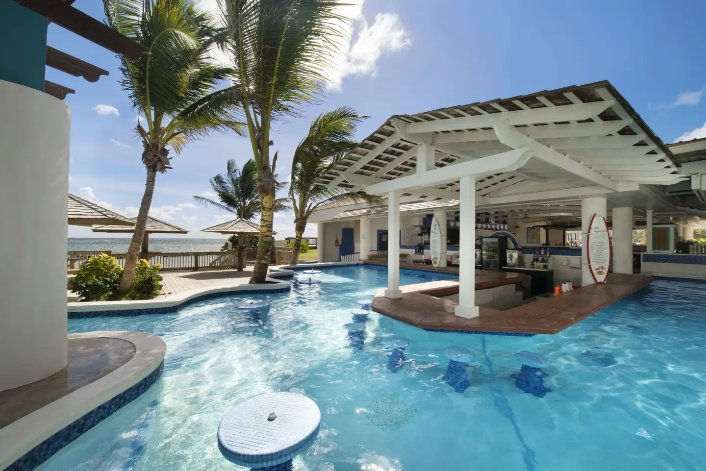 Swim-up bar set in a blue pool beside palms at Coconut Bay Beach Resort & Spa.