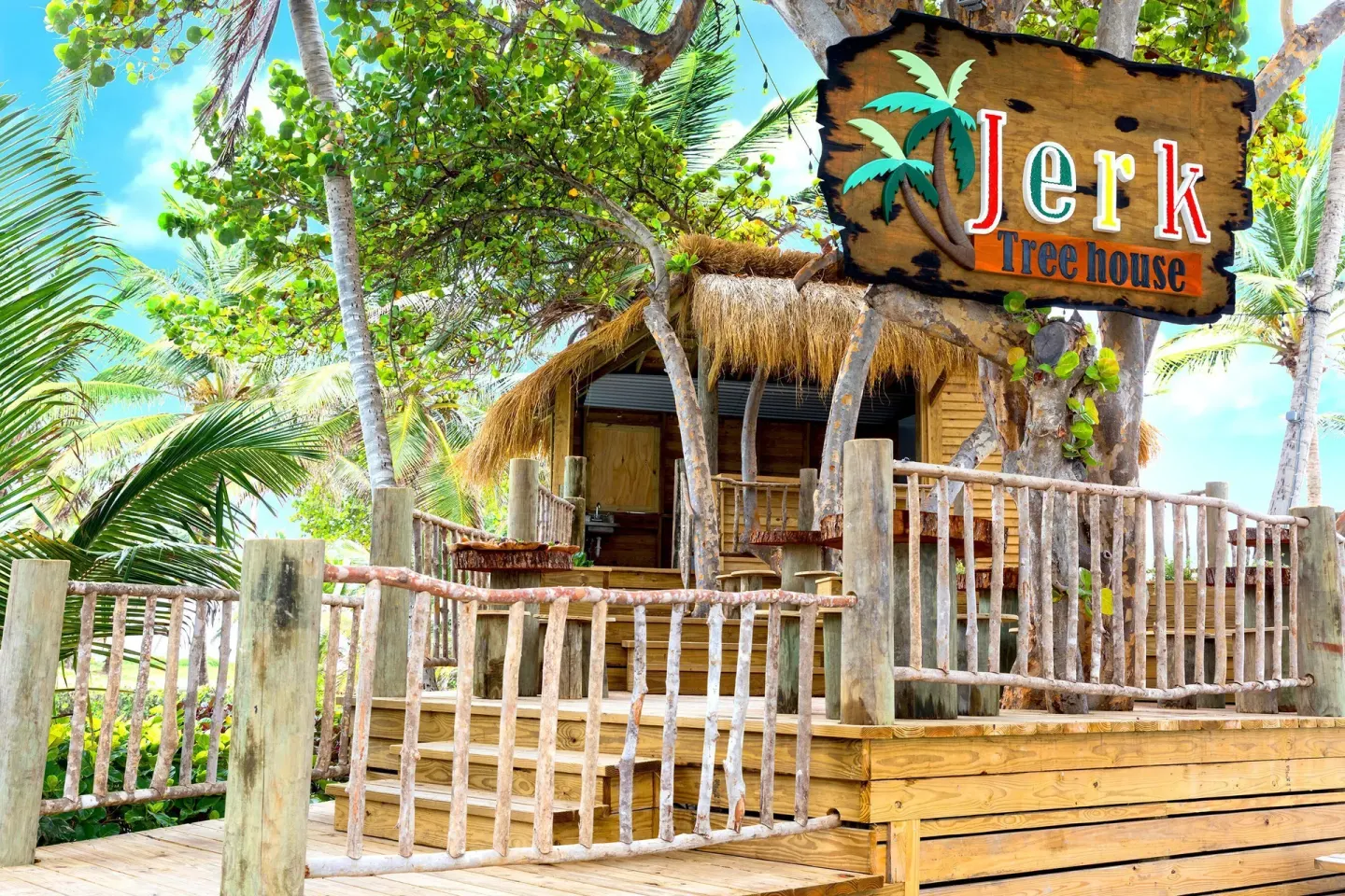 Jerk Treehouse deck and sign among palms at Coconut Bay Beach Resort & Spa.