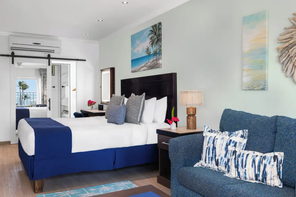Harmony JR Suite Partial Ocean View king bed at Coconut Bay Beach Resort & Spa with sofa and vanity mirror.