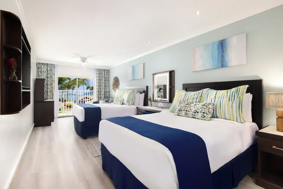 Two-bed Harmony JR Suite Partial Ocean View room at Coconut Bay Beach Resort & Spa with balcony beyond.